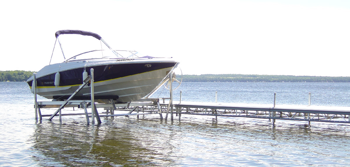 Speed boat on cantilever lift next to aluminium docking system